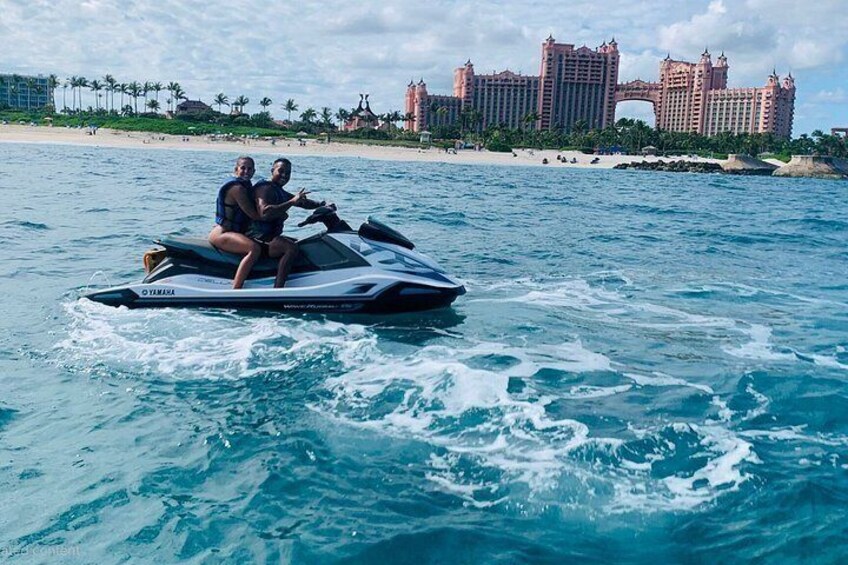 A jet ski on the water with a resort and palm trees in the background. 4