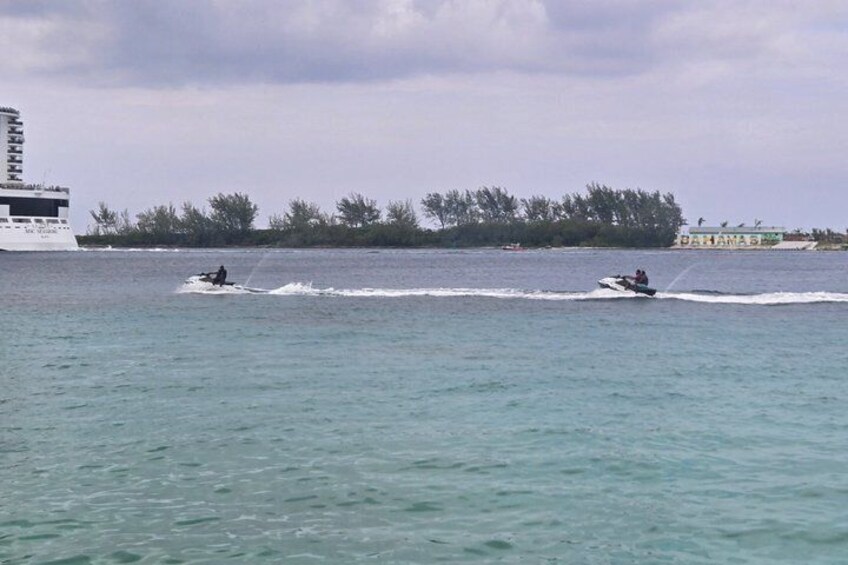 A person jet-skiing on calm waters with a cruise ship and a building labeled 'PANAMA' in the background. 2