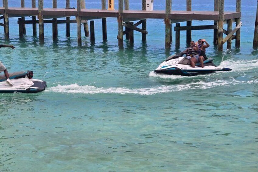Two jet skis on a clear waterway with a wooden pier in the background. 3
