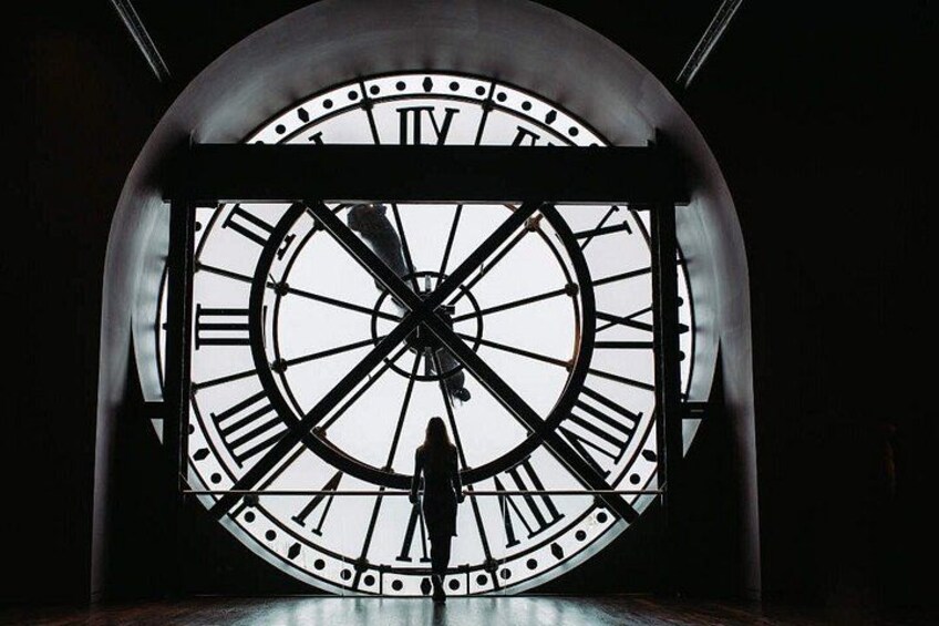 A large clock with Roman numerals and a silhouette of a person. 5