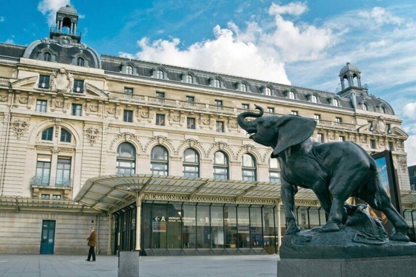 A large building with classical architecture, a glass entrance, and a bronze elephant statue in front. 4