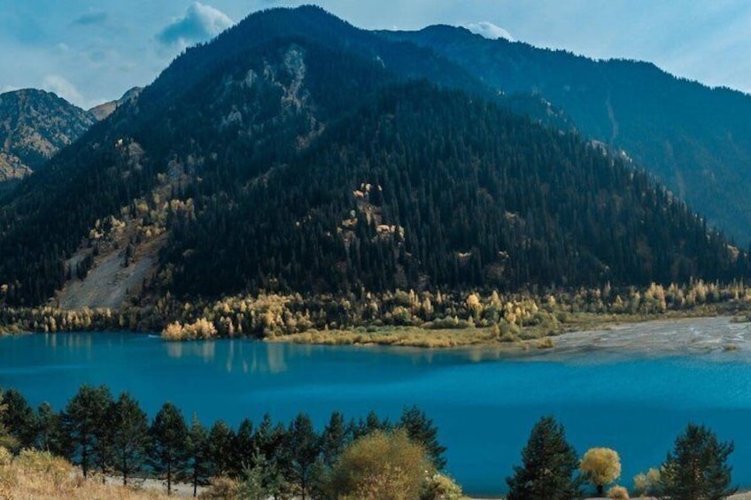 A mountain landscape with a clear blue lake and dense forest. 2