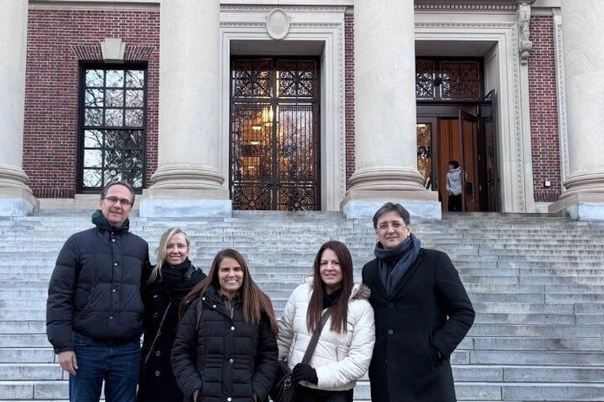 A group of people standing in front of a building with a large ornate door and steps. 3