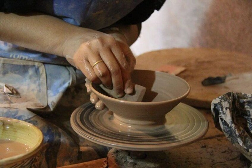 A person shaping a clay pot on a pottery wheel. 3