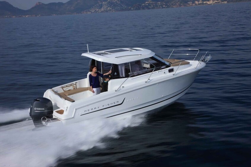 A white motorboat named 'Merry Fisher' with a Yamaha outboard motor, moving on calm water with a mountainous coastline in the background. 5