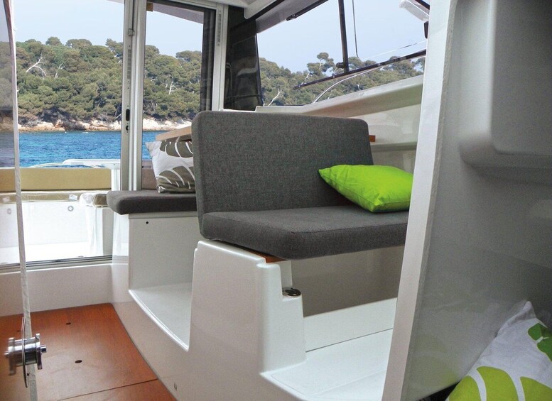 A boat interior with a cushioned seat and a window overlooking a coastal area with trees and water. 4