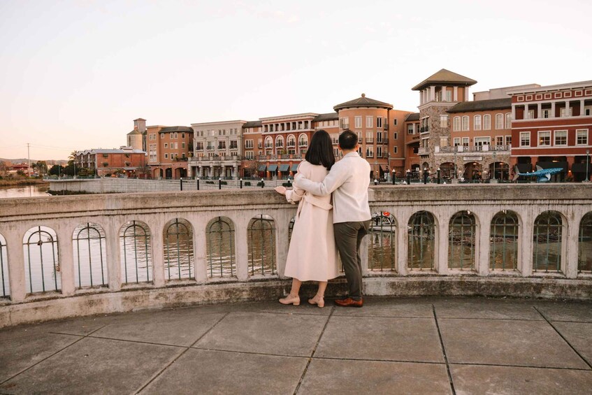 A couple standing on a waterfront promenade with historic buildings in the background. 5