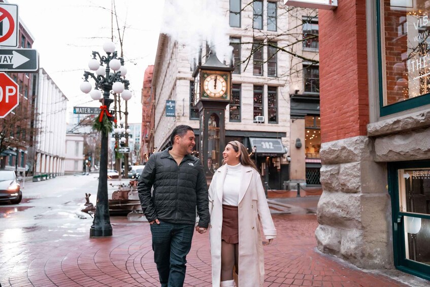 A couple walking on a brick street with a clock tower, a stop sign, and a building with a 'Water' sign in the background. 3