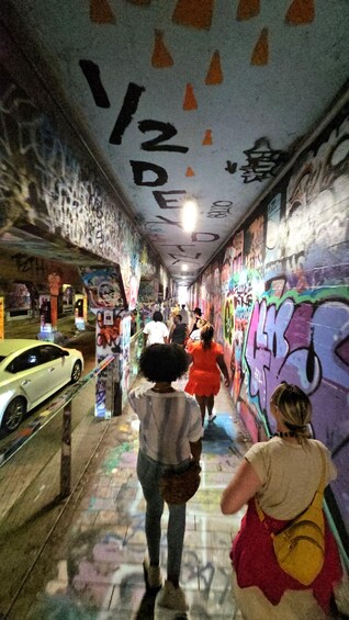 A graffiti-covered tunnel with people walking. 3