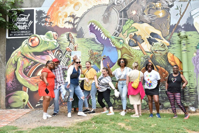 A mural with dinosaurs and people posing in front of it. 1