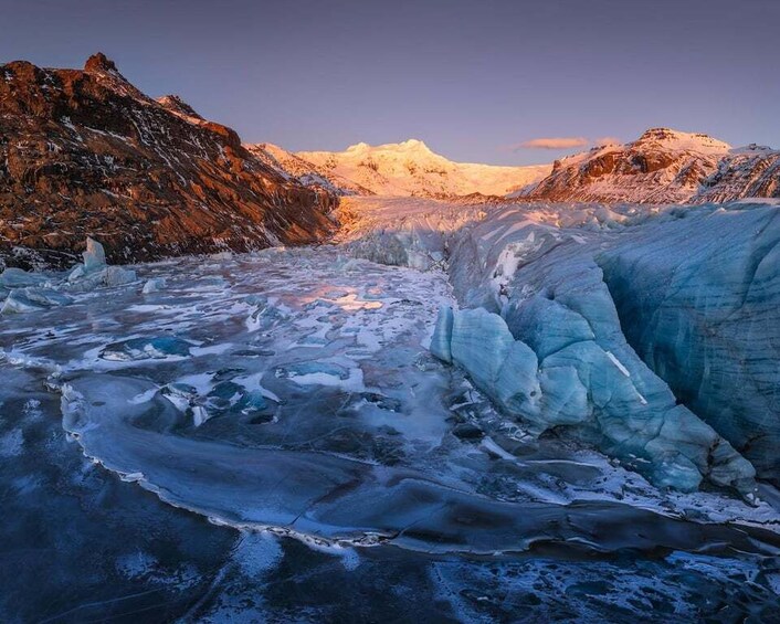 A glacier with ice formations and a mountain range in the background. 5