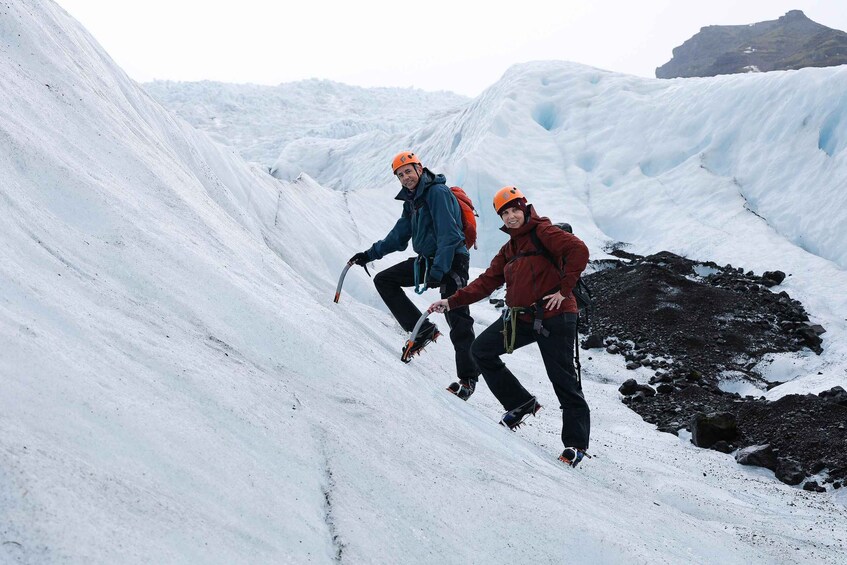 Two people climbing a snowy slope with ice formations in the background. 4