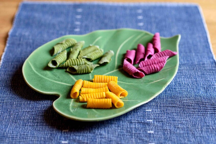 A green plate with pasta shapes on a blue cloth. 4