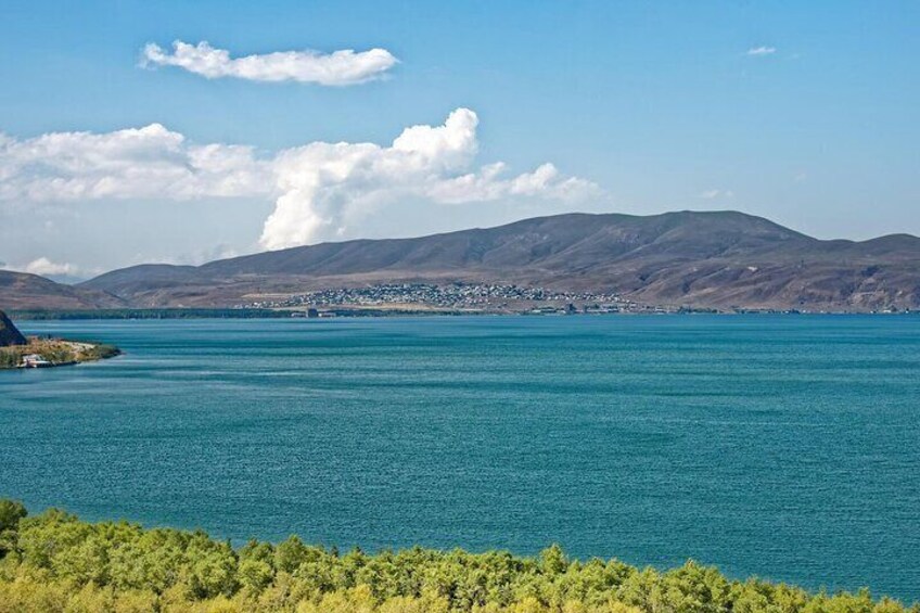 A large body of water with a distant shoreline, mountains, and a clear sky. 4