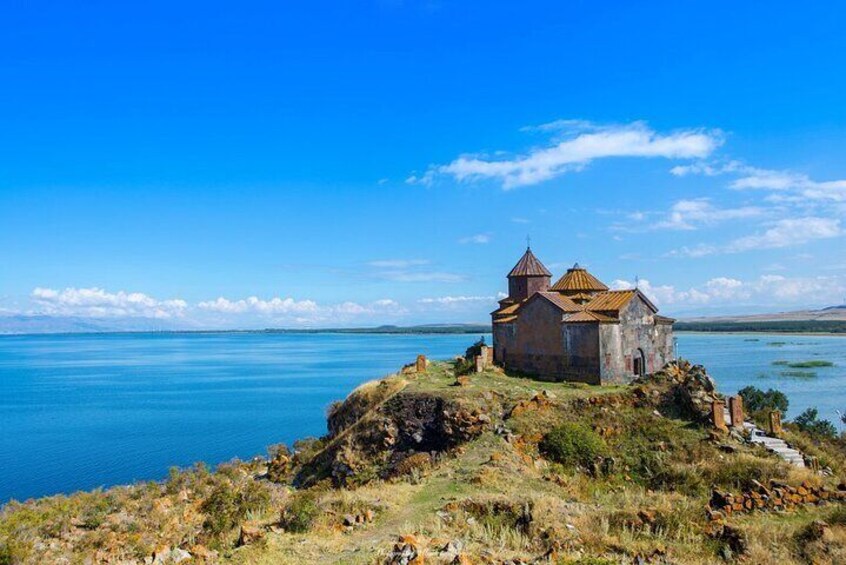 A small stone church on a cliff overlooking a calm lake. 3