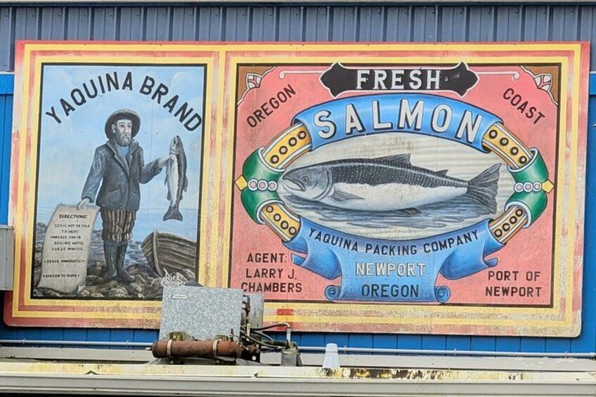 A mural advertising Yaquina Brand and fresh Oregon salmon, with a fishing boat and a man holding a fish. 3