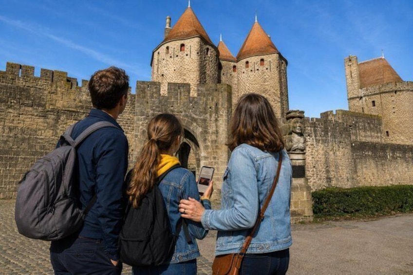 Three people standing in front of a historic stone castle with a round tower. 4