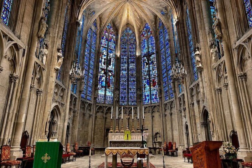 A cathedral interior with high vaulted ceilings, stained glass windows, and ornate stone columns. 5
