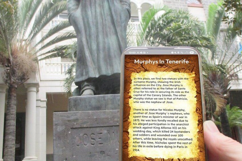 A statue of a man with a plaque reading 'Jose Murphys' in a plaza with palm trees and a building in the background. 5