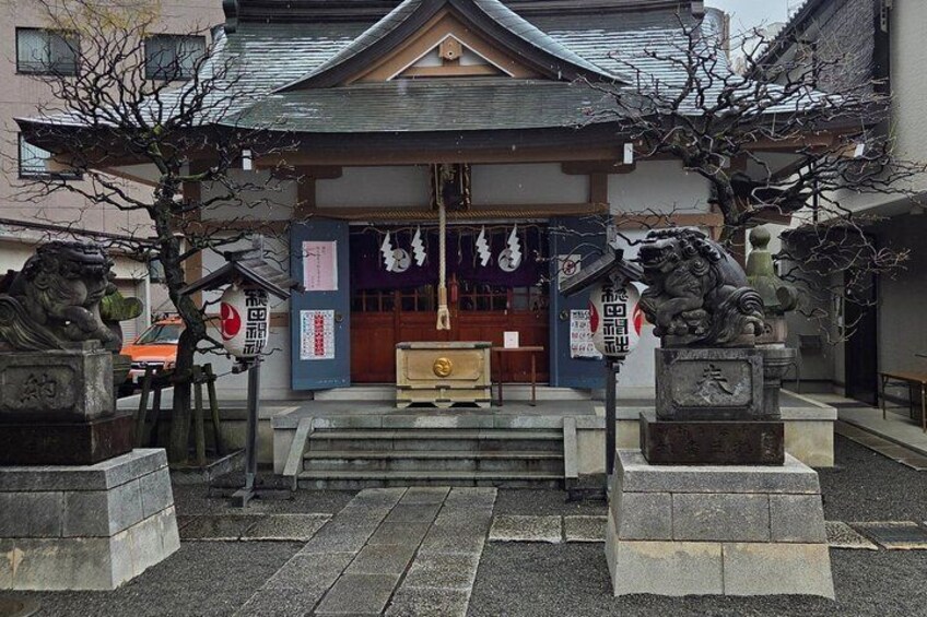 A traditional Japanese building with a tiled roof, stone lion statues, and a wooden gate. 3