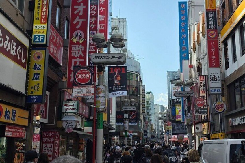 A busy urban street with numerous commercial signs and storefronts. 4