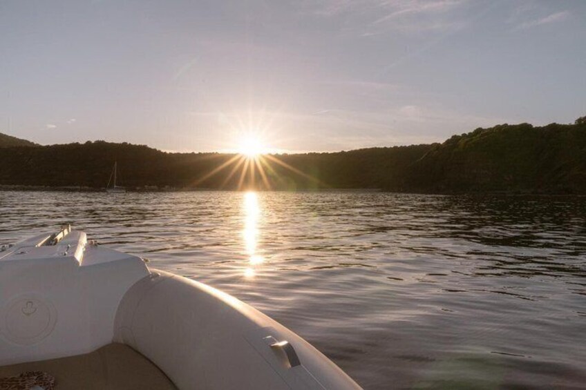 A boat on calm water with the sun setting in the background. 3