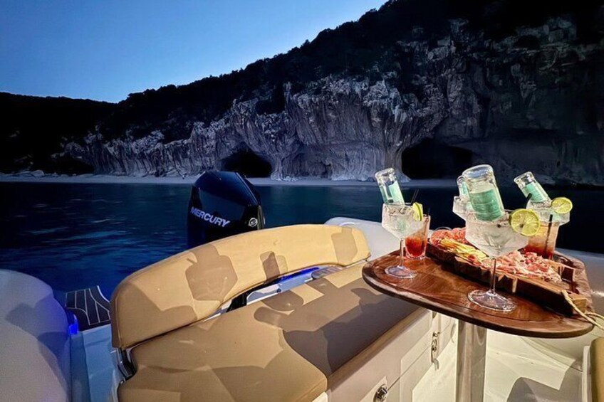 A boat with a table set for a meal, surrounded by water and cliffs. 5