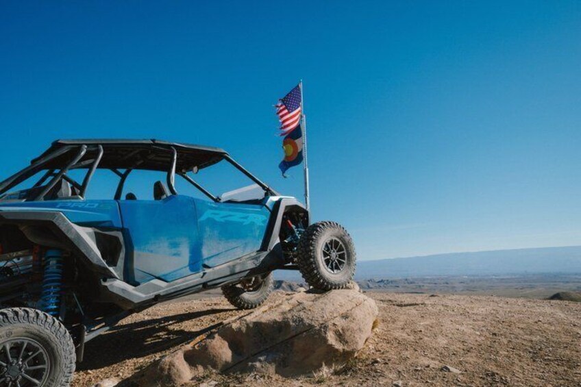 A blue off-road vehicle with an American flag on a rocky terrain. 3