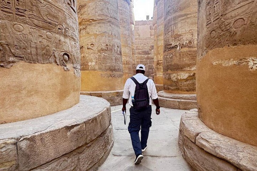 A man walking through a narrow passageway with ancient carvings on the walls. 2