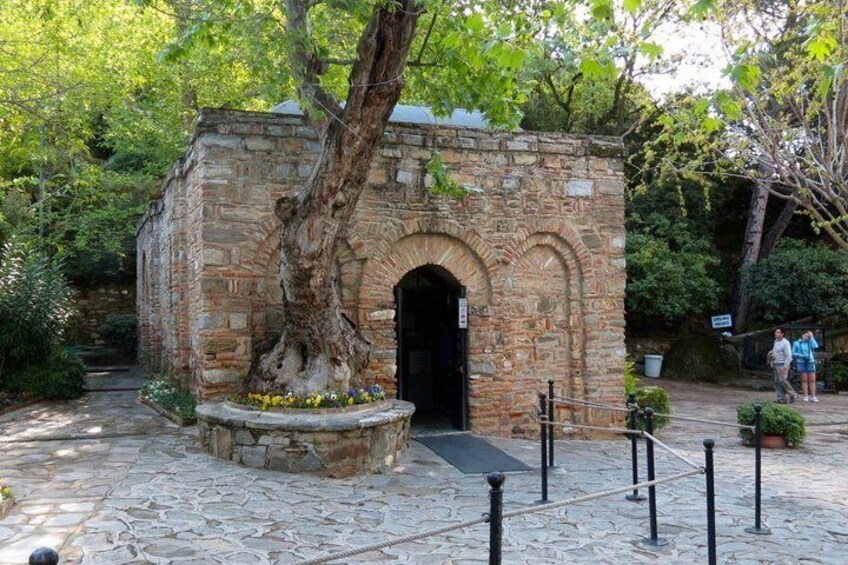 A stone structure with an arched entrance, surrounded by a stone pathway and greenery. 1
