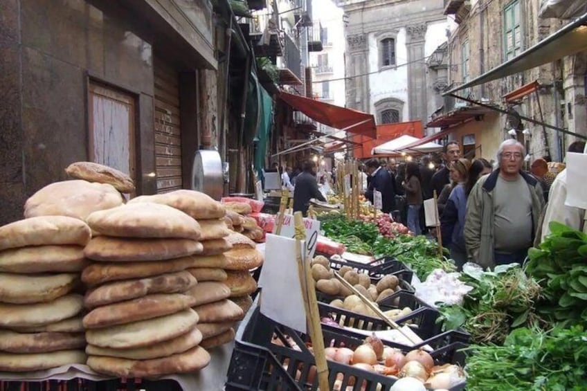 An outdoor market with bread and vegetables on display. 5