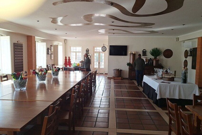 A long dining table with chairs, a clock on the wall, and a plant on the side. 3