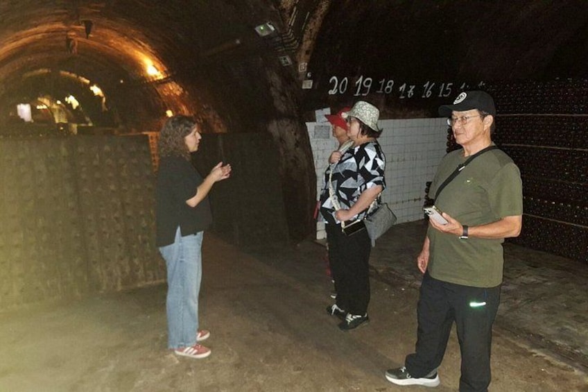 A group of people in a dimly lit tunnel with a wall displaying numbers. 2