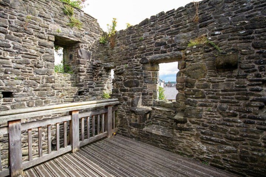 An ancient stone wall with a wooden railing and a window. 4