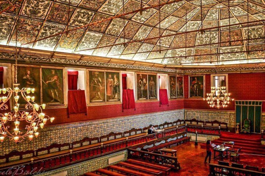 An ornate hall with a high, patterned ceiling, red walls, and a central aisle. 3