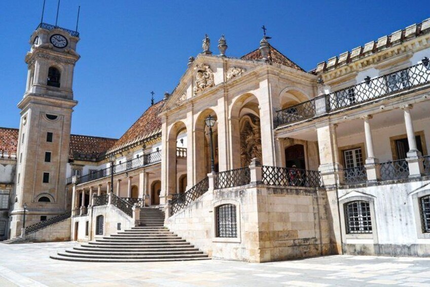 A historic building with a clock tower, a grand staircase, and a balcony with a railing. 5
