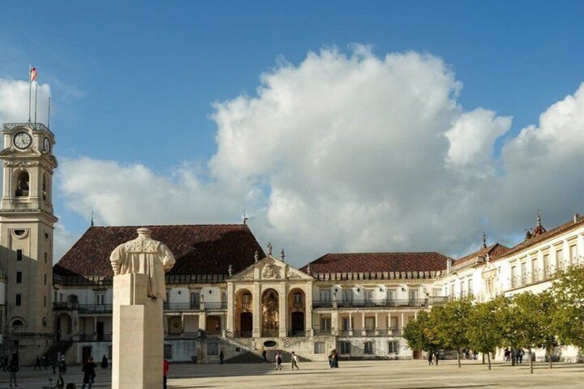 A historic plaza with a clock tower, ornate buildings, and a statue. 4