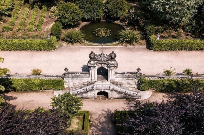 An aerial view of a historic gate with intricate carvings, surrounded by well-maintained gardens and a pond. 2