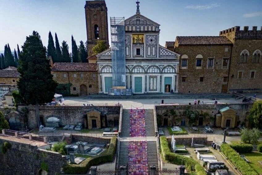 A historic building with a clock tower, surrounded by a well-maintained garden and a paved area with colorful decorations. 5