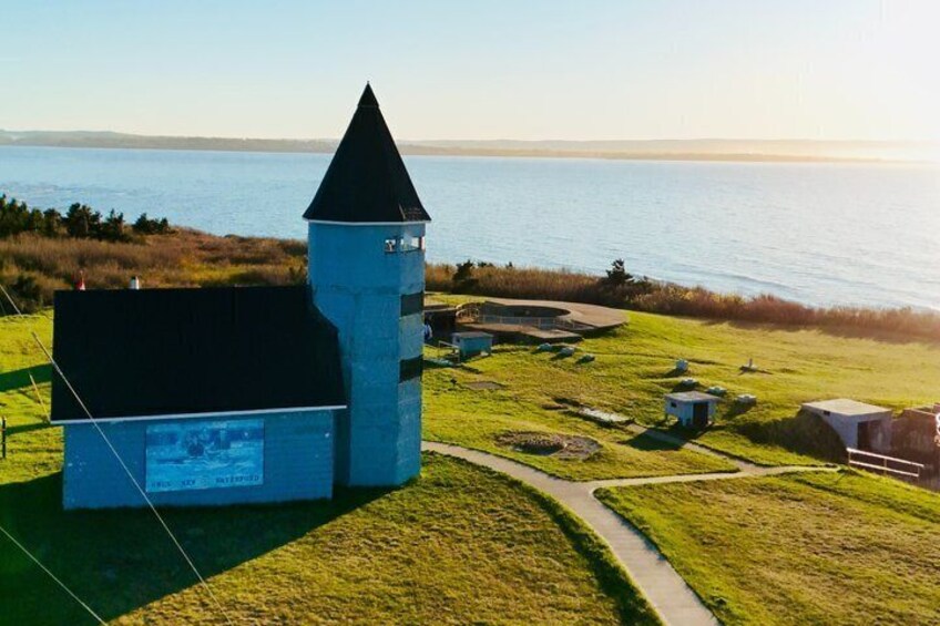 A church with a tower and a body, surrounded by a grassy field and a body of water. 2