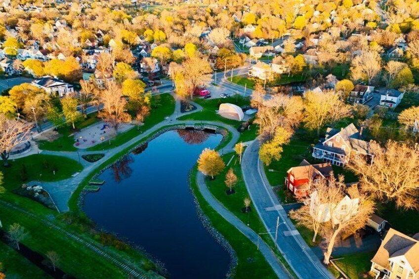 An aerial view of a residential area with a central pond, surrounded by houses and autumn-colored trees. 3