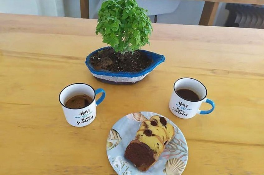 A wooden table with two coffee mugs, a plate with a slice of cake, and a potted plant. 3