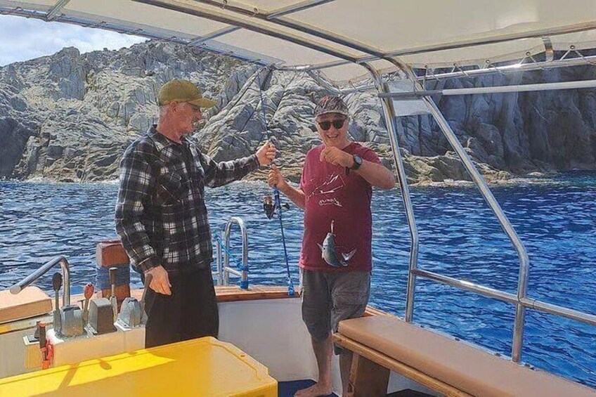 Two people on a boat with rocky cliffs in the background. 5