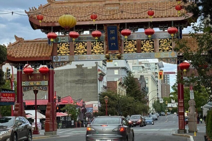 A street with a traditional Chinese gate, cars, and buildings. 3