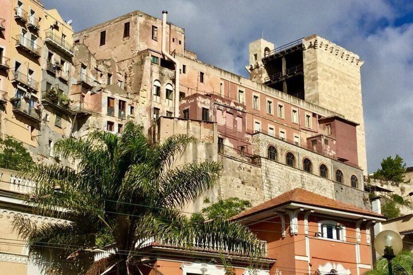 A historic building with multiple stories, some with balconies, and a palm tree in the foreground. 5