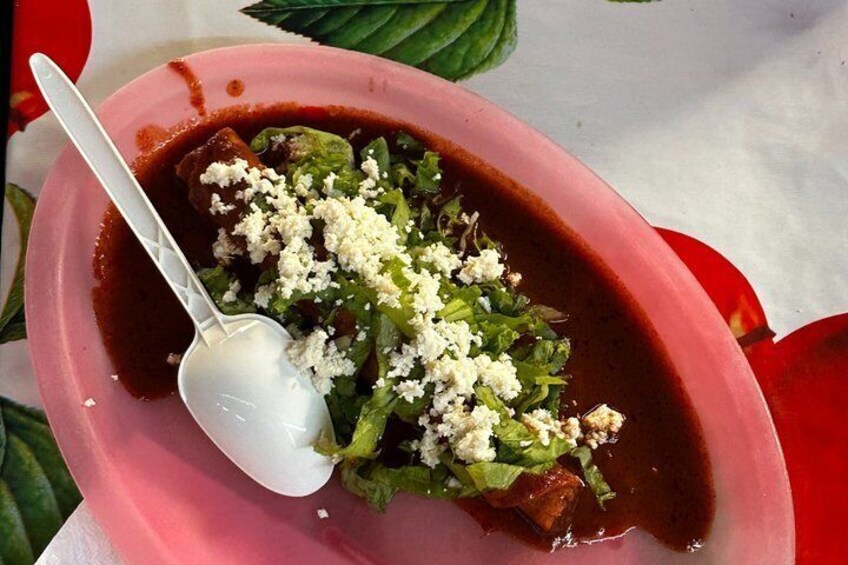 A bowl of food with a spoon, garnished with cheese. 1