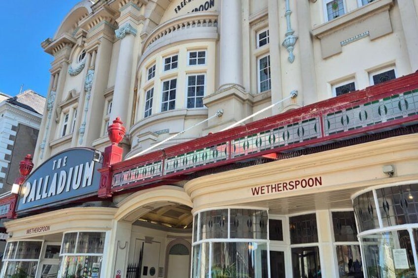 The Palladium theater with a red awning and a sign for Wetherspoon. 4