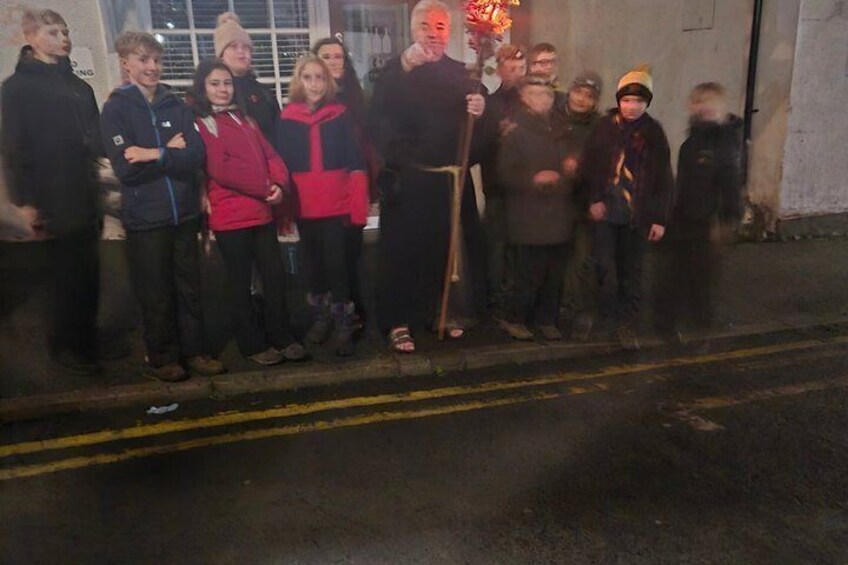 A group of people standing on a sidewalk at night. 3
