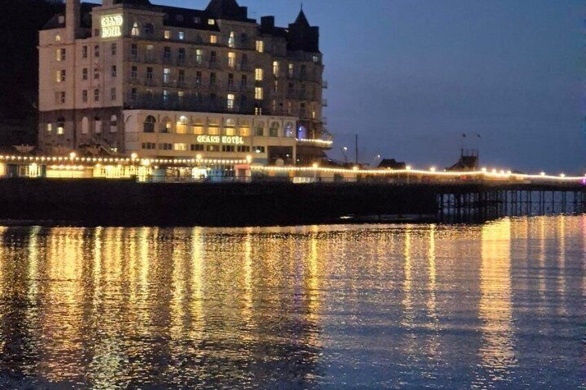A waterfront hotel with illuminated windows and a pier extending into the water. 4