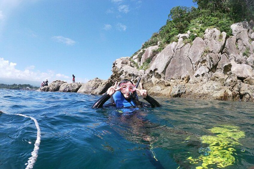 A person kayaking in clear blue water with rocky cliffs in the background. 2